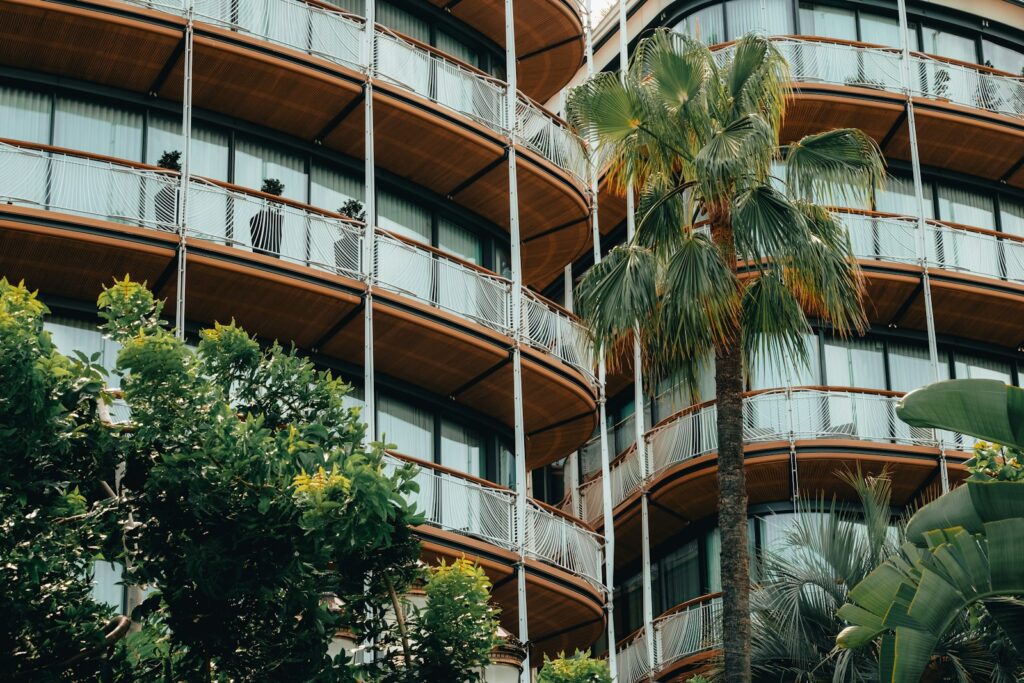 a tall building with balconies and palm trees in front of it